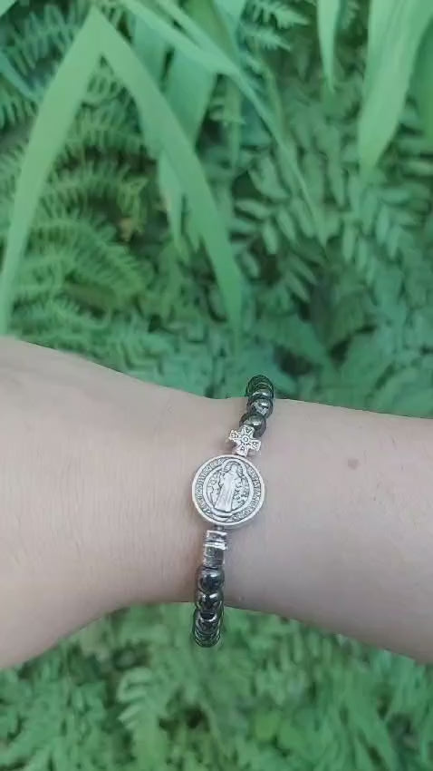 Pulseira de hematita com medalha de São Bento no pulso